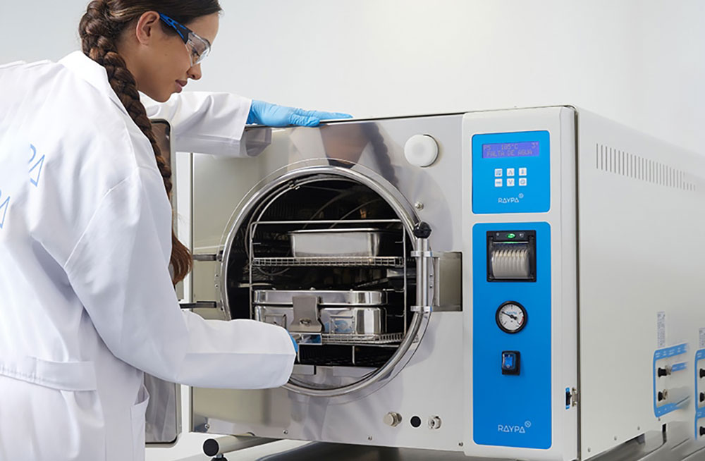 خانمی که با رعایت اصول کار با اتوکلاو در حال استریل کردن ظروف آزمایشگاه است.